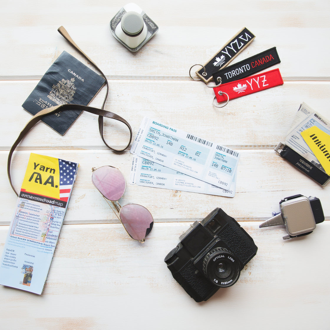 Travel items including a passport, sunglasses, camera, and boarding pass on a wooden surface.